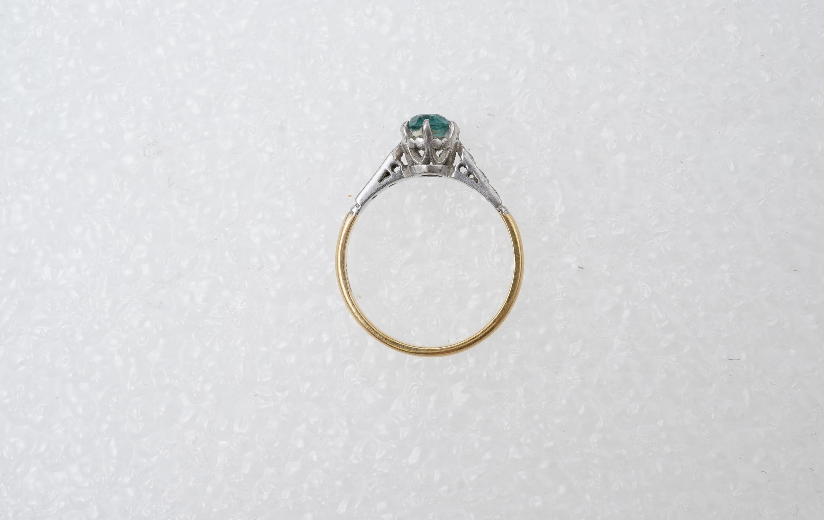 A zircon and diamond ring, mid 20th century, claw-set with a brilliant-cut blue zircon measuring approximately 5mm diameter, to shoulders set with rose-cut diamonds, mounted in gold, size N, stamped 18CT, gross weight ap